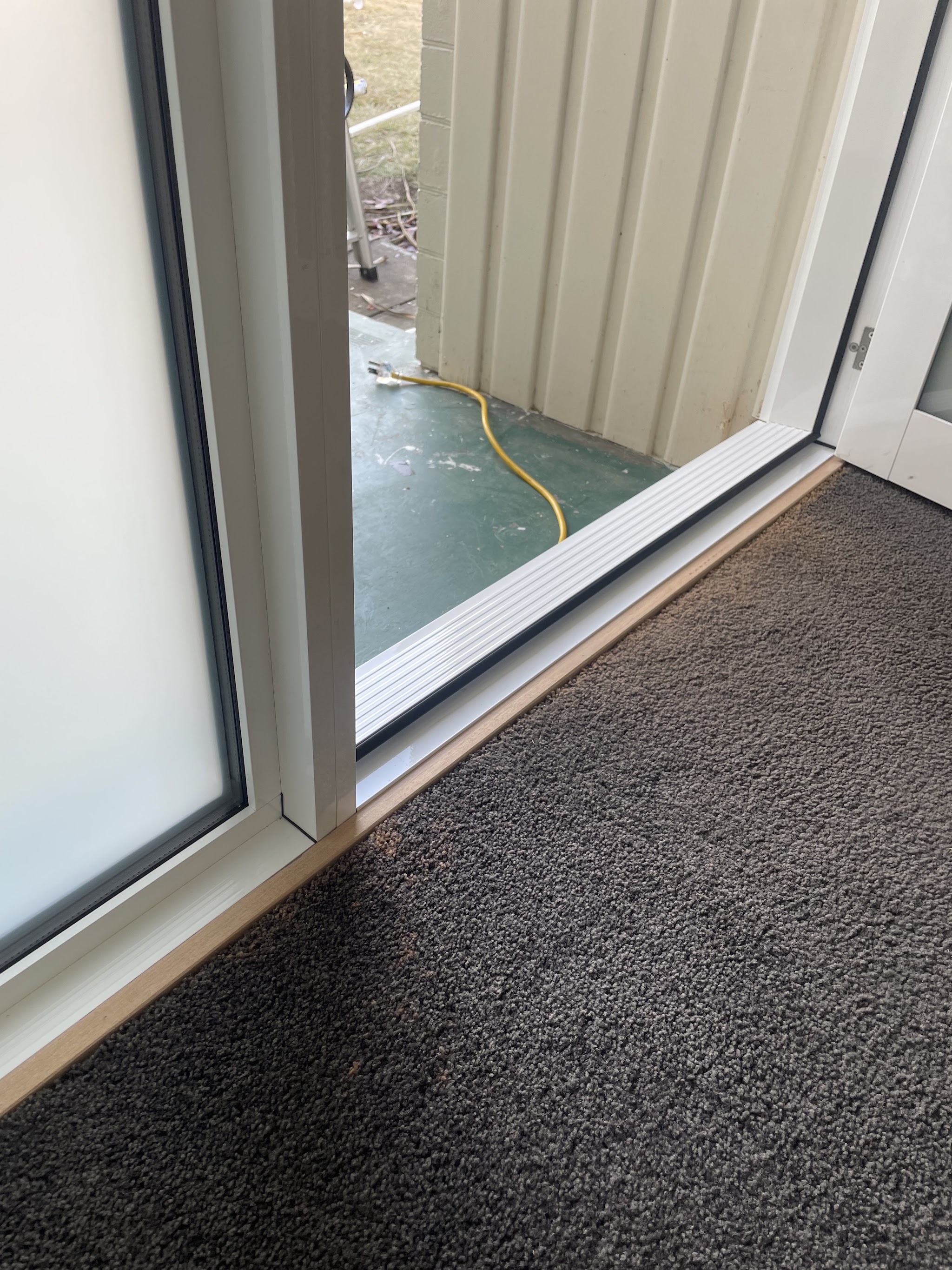 Close detail of a finished white framed sliding door sill meeting the carpet inside