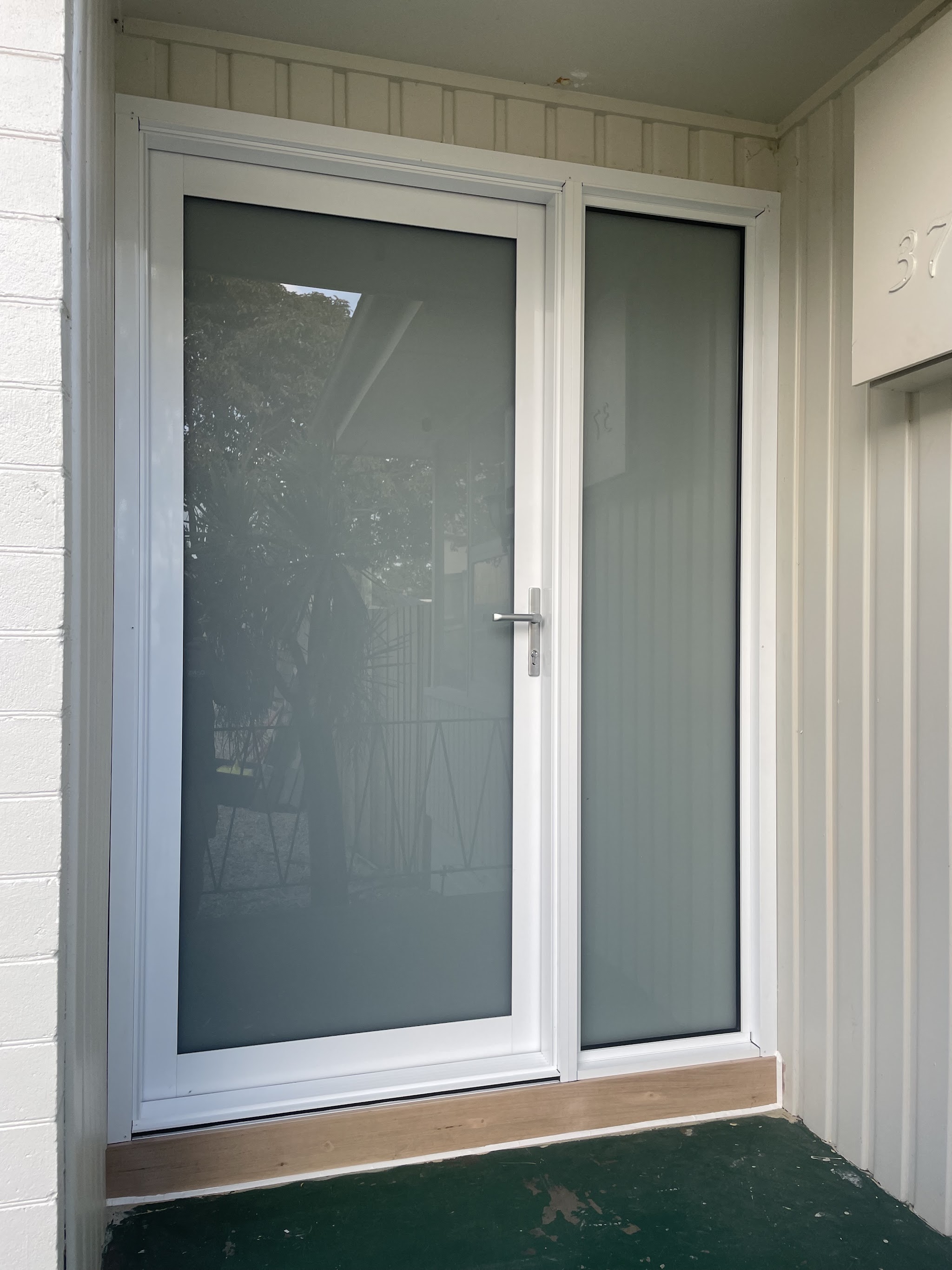 A finished white framed entry door with obscure glazing and a matching sidelight